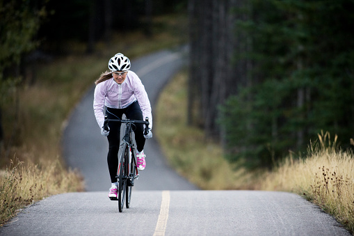 A woman rides her road bike along the Trans Canada Trail bikepath near Canmore, Alberta, Canada in the autumn.