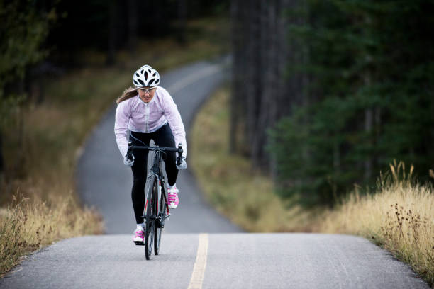 uma mulher monta sua bicicleta de estrada ao longo do bikepath de trans canadá trilha perto de canmore, alberta, canadá no outono. - racing bicycle - fotografias e filmes do acervo