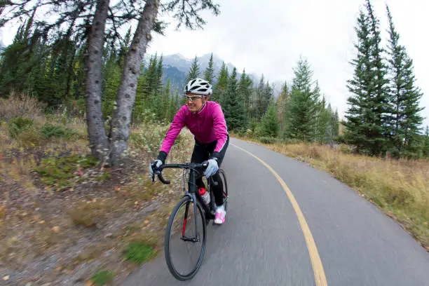 She is riding a road bike and wearing warm clothing.