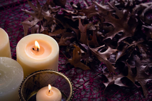 istock Lit candles and dry leaves on table 864724582