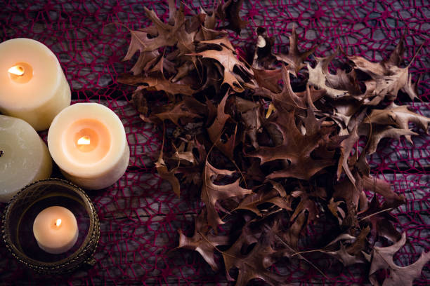 istock Lit candles and dry leaves on table 864724590