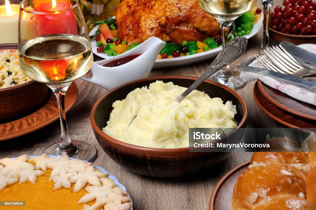 mashed potatoes A bowl of mashed potatoes on a table among the pumpkin pie, baked turkey, cranberry-orange sauce,   a glass of white wine for Thanksgiving Mashed Potatoes Stock Photo