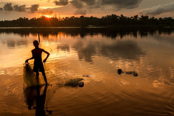 Ankaninofy, Madaagscar, November 17, 2016:  A Malagasy fishrman taking back his fishing net at sunset in the Pangalanes Canal, east of Madagascar