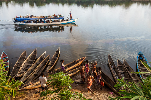 Aneho, Togo - November 20, 2019: A group of men repair a traditional boat in Anheo, Togo, West Africa. All reusable parts are used again to avoid any waste. Each piece of recycled and re-useable wood is a precious raw material. A man uses a hoe.