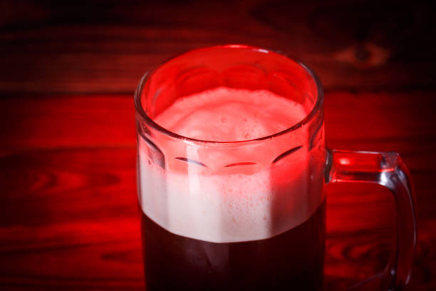 Beer mug on bar counter, bartender and customers in background, focus on beer