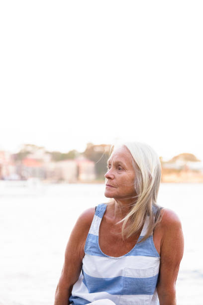 istock Mature woman sitting at the harbour, background with copy space 864756364