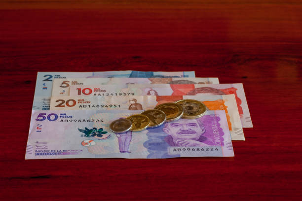 Colombia's International Award Winning Coinage are arranged on the new Colombian banknotes. On display are the 1000, 500, 200, 100 and 50 Peso coins. On the faces of the coins are images of a turtle, frog, bird, flower and bear. The higher denomination coins of 1000 and 500 have a bi-metal design. The new 50,000 Peso note carries the image of Colombia's Nobel Prize winning author, Gabriel García Márquez. Photo shot in studio environment; horizontal format. Camera: Canon EOS 5D MII. Lens: Leica APO Summicron-R 90 mm F2 ASPH. colombia, américa del sur - galardonado internacional de invención colombiana a los nuevos billetes dispuestos en una mesa de palo de rosa. la nota de 50 mil pesos en la parte superior lleva la imagen del nobel laureado gabriel garcía márquez.