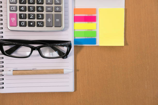 istock sticky note, calculator, ballpoint pen, empty notebook, eyeglasses on office desk. business, accountant concept. Top view with copy space. selective focus. 864793654