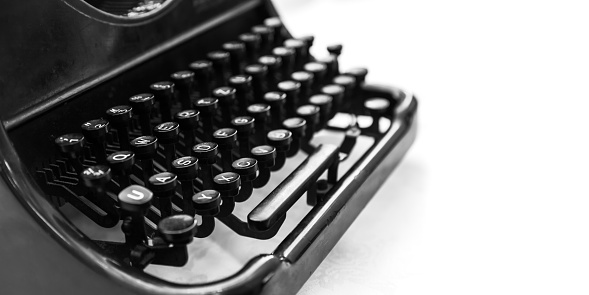 Old manual typewriter machine, closeup fragment with keyboard over white background, black and white photo with soft selective focus