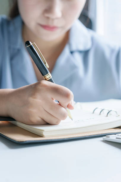 istock young woman writing in notebook by office desk. 864808794