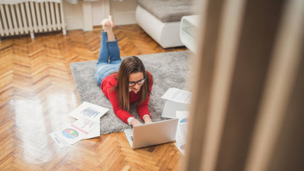 istock Young woman laying on the floor and working 864812306