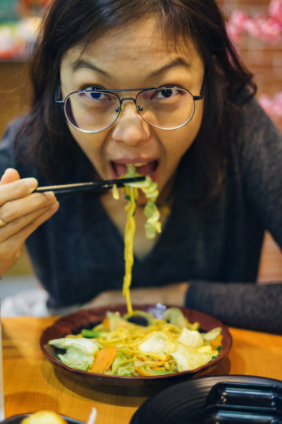 istock Woman eating yakisoba looking toward camera 864820676