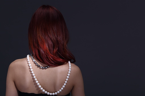 Red Brunette Shinny Hair Style on Asian Make Up Woman, Portrait half body with jewelry Pearl necklace south sea white on back rear side, studio spot lighting gray background
