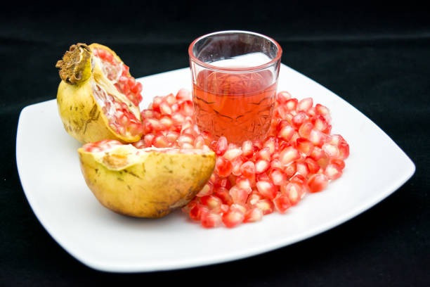 open pomegranade composition with a glass full of pomegranade juice on dark background
