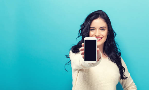 istock Young woman holding out a cellphone 864865524