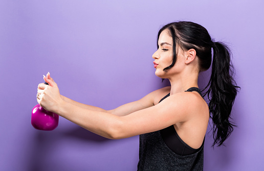 Happy young woman working out with a kettlebell
