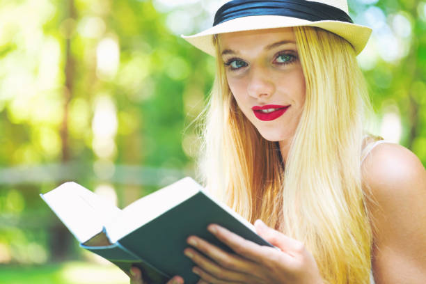 istock Young woman reading a book outside 864865678