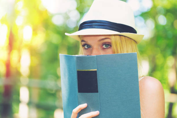istock Young woman reading a book outside 864865682