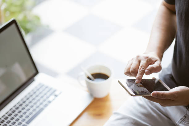 istock Smartphone in young man hand with blur laptop and coffee background , selective focusing . 864866114