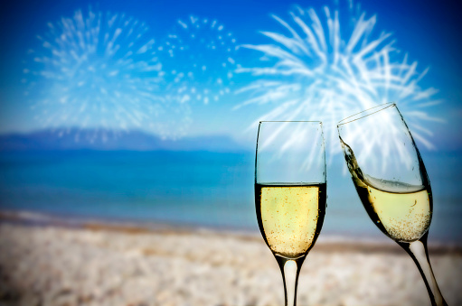 Glasses of champagne on the beach against the sky and blue sea