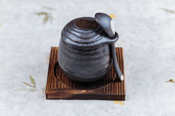 istock Japanese custard pudding torched caramel on top served in black ceramic cup on wooden plate with lid and spoon on washi (Japanese paper). 864875820