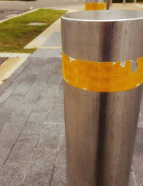istock Metal bollard with yellow stripe on public walkway. 864897342