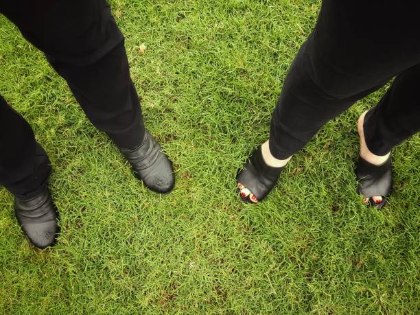 istock Two people in black standing on lawn. 864899628
