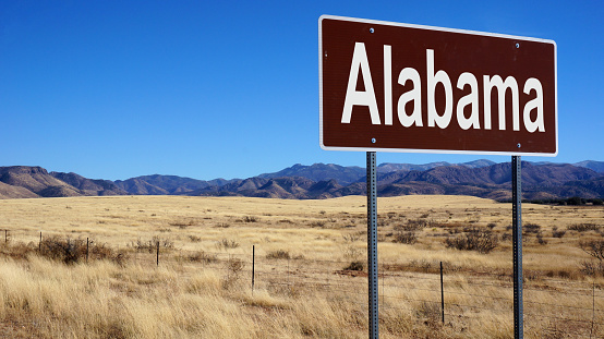 Alabama road sign with blue sky and wilderness
