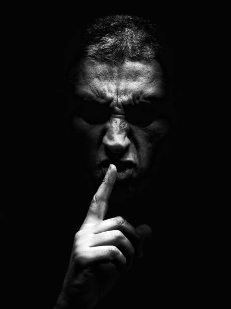 istock Furious mature man with an aggressive look making the silence sign in a violent and threatening way. 864918616