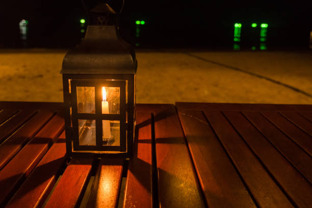 A candle lamp on a table by the sea at night