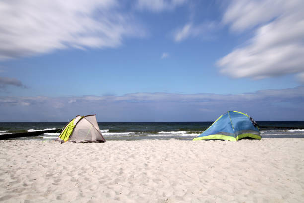 istock Windbreak tents on summer beach with blue sky 864923046