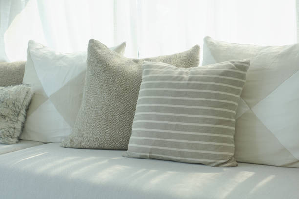 istock Stripe and beige pillows setting on sofa next to window 864925222