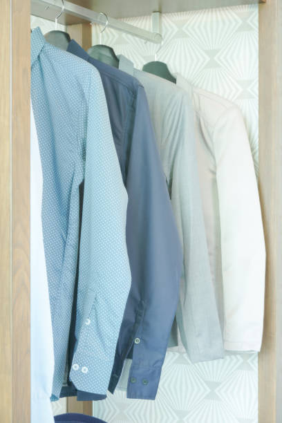 istock Shirts and men's suit hanging in closet 864925570