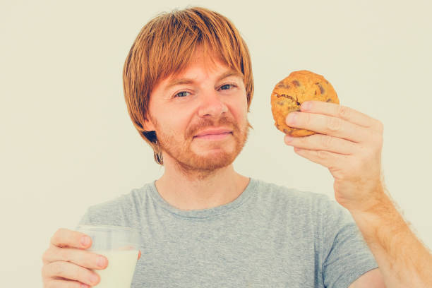istock Content Red-haired Man Eating Cookie With Milk 864926416