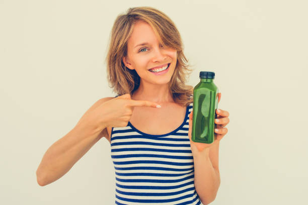 istock Cheerful young woman pointing at green bottle 864926600