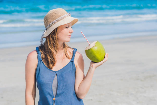 istock Attractive young woman drinking coconut water on the beach 864942908