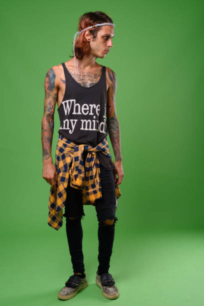 rebellious young man with body tattoos against green background - tattoo men profile punk imagens e fotografias de stock