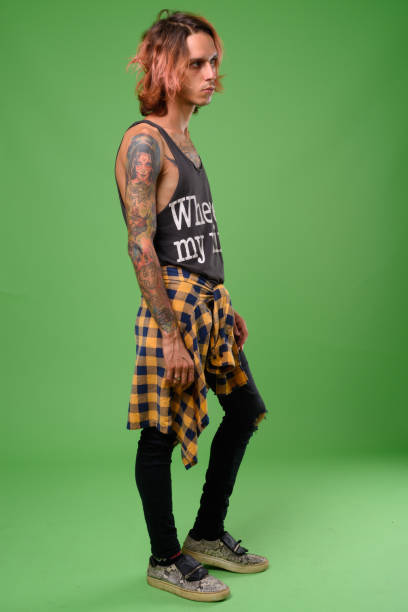 rebellious young man with body tattoos against green background - tattoo men profile punk imagens e fotografias de stock