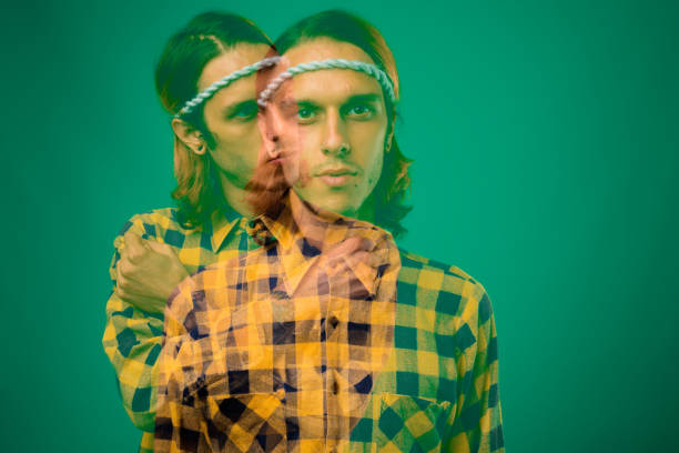 istock Young man with long hair wearing yellow checked shirt against green background 864947708