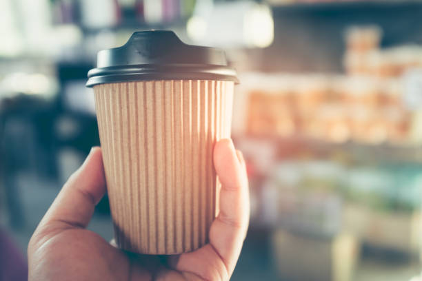 istock Hand holding take away paper hot coffee drinking cup with bright sunlight. 864954070