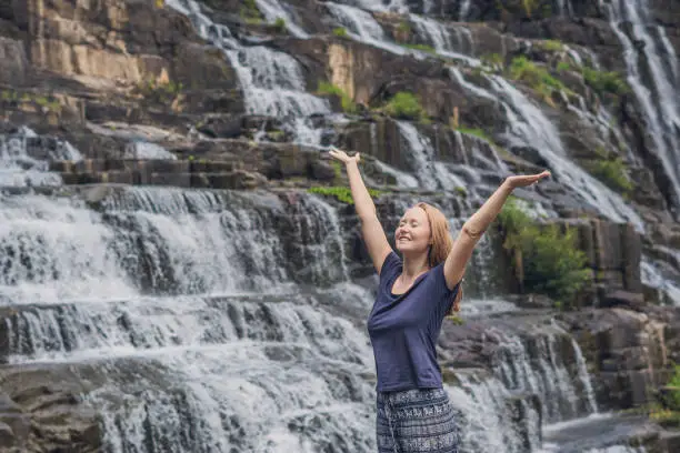 Photo of Young woman hiker, tourist on the background of Amazing Pongour Waterfall is famous and most beautiful of fall in Vietnam. Not far from Dalat city estimate 45 Km. Dalat, Vietnam