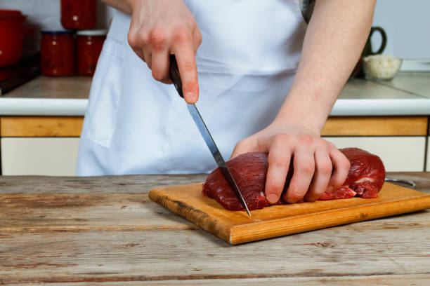 istock Butcher cutting pork meat on kitchen 864955680