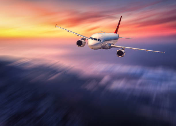 istock Modern airplane mith motion blur effect is flying over low clouds at sunset. Landscape with passenger airplane, blurred clouds, sunlight in dusk. Passenger aircraft. Business travel. Commercial plane 864965752