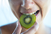 Woman Biting Kiwi Slice