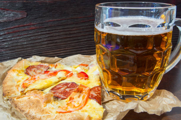 istock Light beer in glass and fragrant Italian pizza. 864975932