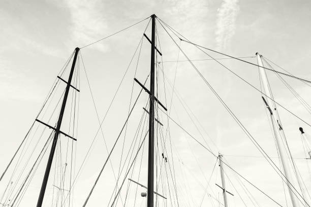 Masts of sailboat and blue sky. Summer vacation. Transport theme. Black and white photo.