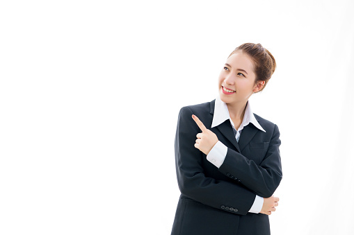 Smiling young Asian businesswoman in black suit and white t-shirt pointing finger isolated on white background