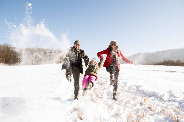 father and mother with their daughter, playing in the snow. - family winter walking fun imagens e fotografias de stock