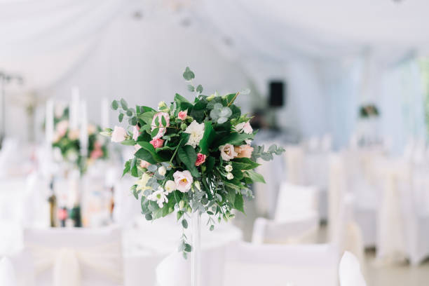 istock Beautiful wedding floral decoration on a table in a restaurant. White tablecloths, bright room, candles, close-up shooting. The event, happiness, honeymooners. Soft bokeh white background 865015216