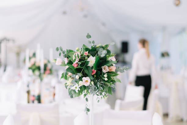 istock Beautiful wedding floral decoration on a table in a restaurant. White tablecloths, bright room, candles, close-up shooting. The event, happiness, honeymooners. Soft bokeh white background 865015236